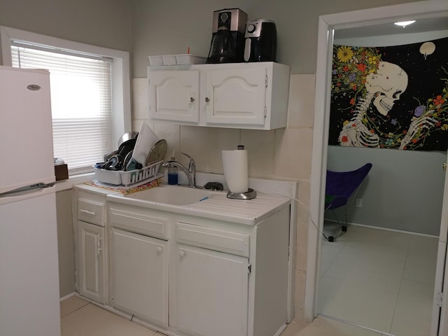 kitchen featuring white fridge, white cabinetry, and sink