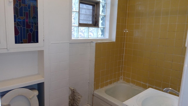 bathroom featuring tiled shower / bath, sink, and tile walls