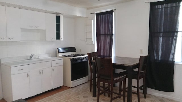 kitchen featuring white cabinetry, tasteful backsplash, and white range with gas stovetop