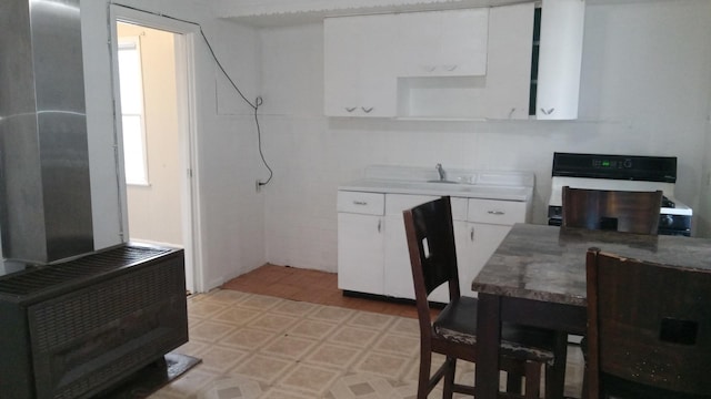 kitchen with white cabinetry, sink, and stove