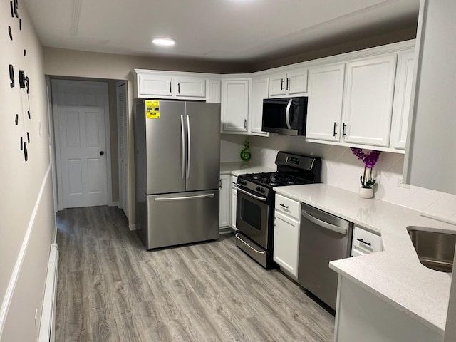 kitchen with white cabinetry, sink, stainless steel appliances, baseboard heating, and light wood-type flooring