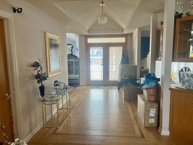 foyer with vaulted ceiling, light hardwood / wood-style floors, and french doors