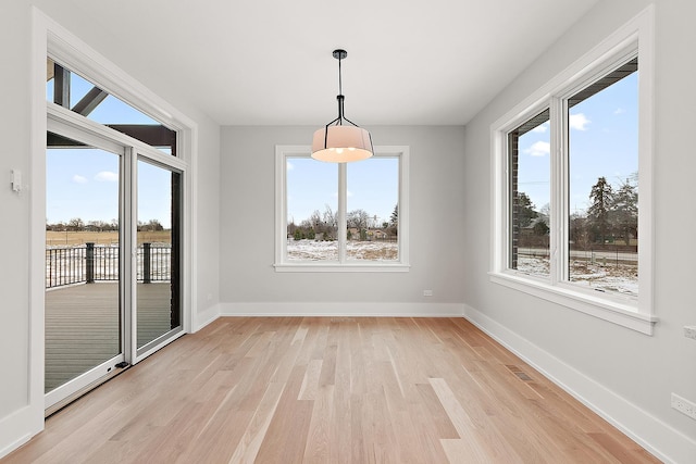 unfurnished dining area with a wealth of natural light, visible vents, light wood-type flooring, and baseboards