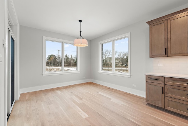 unfurnished dining area featuring baseboards and light wood finished floors