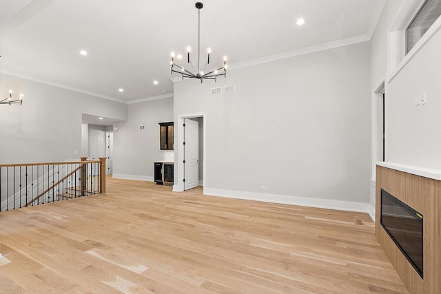 unfurnished living room featuring visible vents, baseboards, an inviting chandelier, and light wood-style flooring