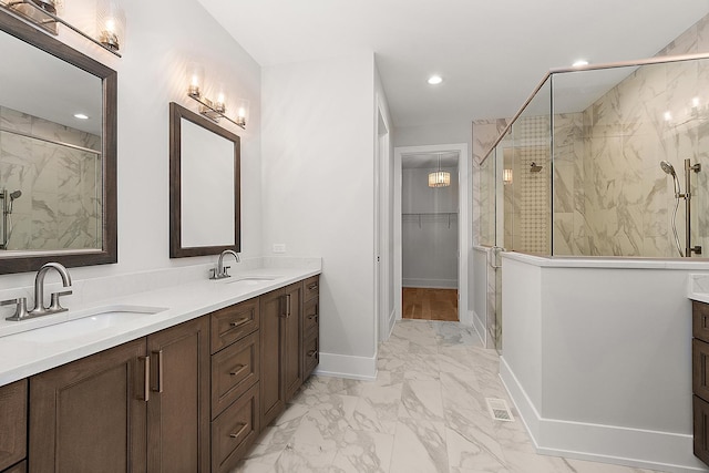 bathroom with a sink, a marble finish shower, marble finish floor, and double vanity