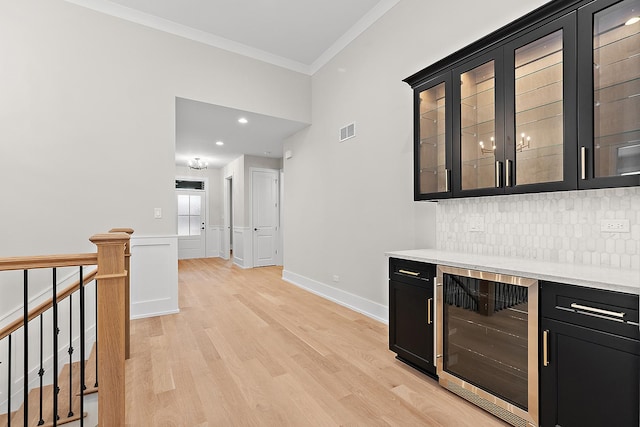 bar with light wood-type flooring, visible vents, beverage cooler, ornamental molding, and backsplash