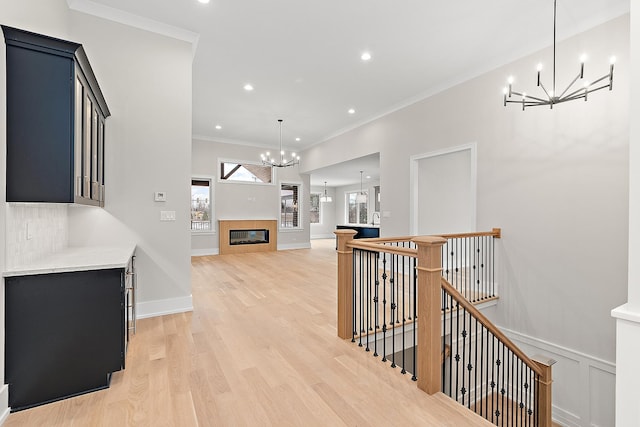 hallway featuring light wood finished floors, crown molding, a chandelier, an upstairs landing, and recessed lighting