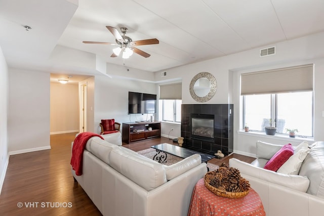 living room featuring ceiling fan, plenty of natural light, dark hardwood / wood-style floors, and a tile fireplace