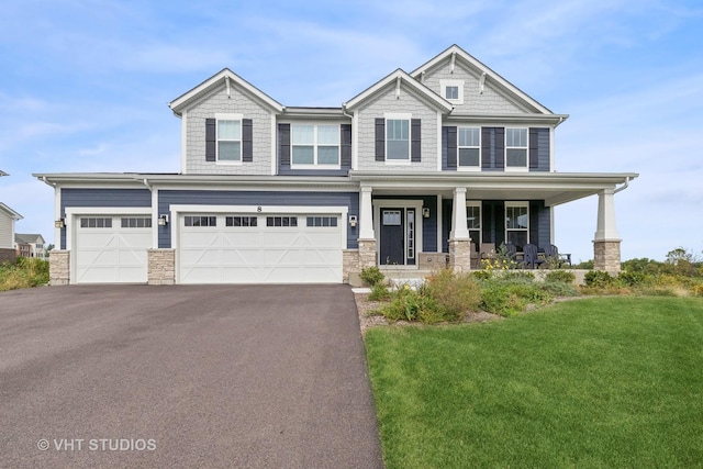 craftsman inspired home featuring a porch, a garage, and a front lawn