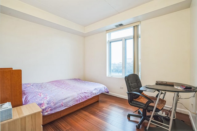 bedroom with a raised ceiling and dark hardwood / wood-style flooring