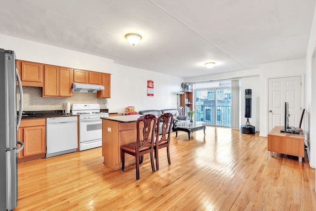 kitchen with tasteful backsplash, a center island, white appliances, and light hardwood / wood-style flooring