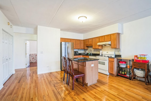 kitchen with a center island, sink, decorative backsplash, light wood-type flooring, and appliances with stainless steel finishes