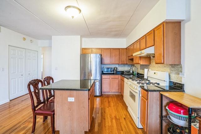 kitchen featuring sink, tasteful backsplash, appliances with stainless steel finishes, a kitchen island, and light wood-type flooring