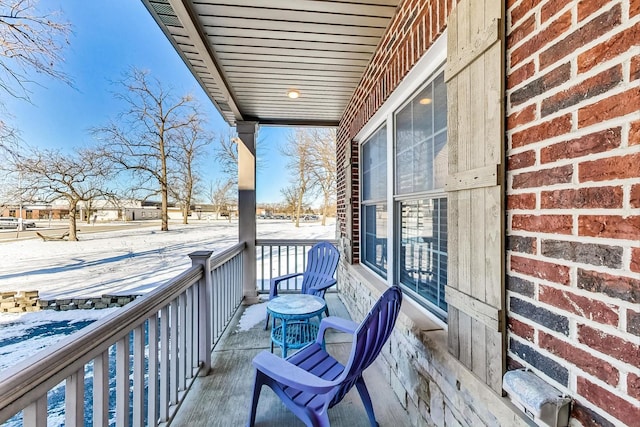 snow covered back of property with a porch