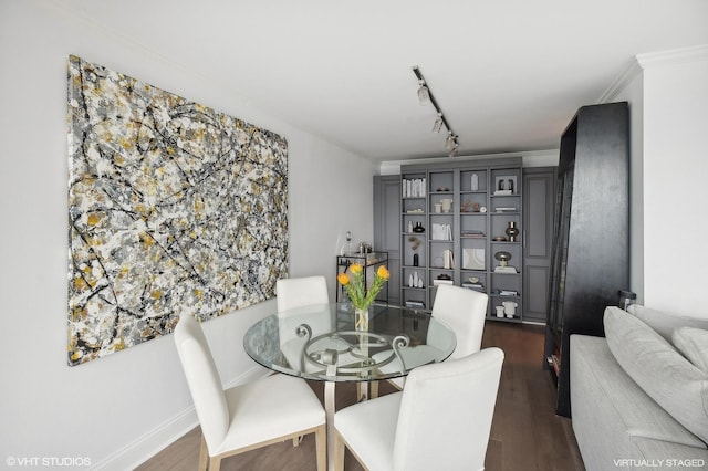 dining area featuring dark hardwood / wood-style flooring, ornamental molding, and rail lighting