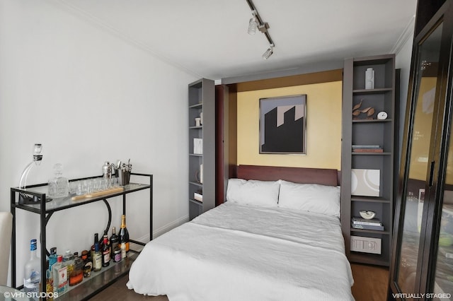 bedroom with crown molding, rail lighting, and dark wood-type flooring