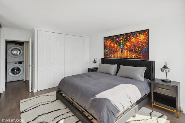 bedroom featuring a closet, crown molding, stacked washer / dryer, and dark wood-type flooring