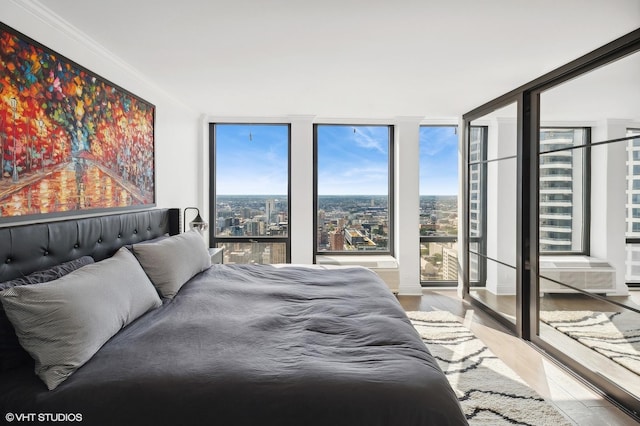 bedroom featuring hardwood / wood-style floors, expansive windows, and ornamental molding