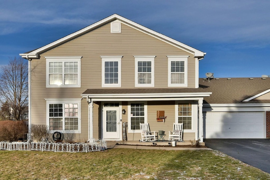 view of front of home featuring covered porch, a garage, and a front lawn