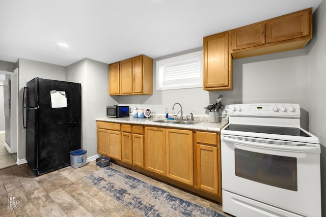 kitchen with electric range, black refrigerator, sink, and light hardwood / wood-style flooring