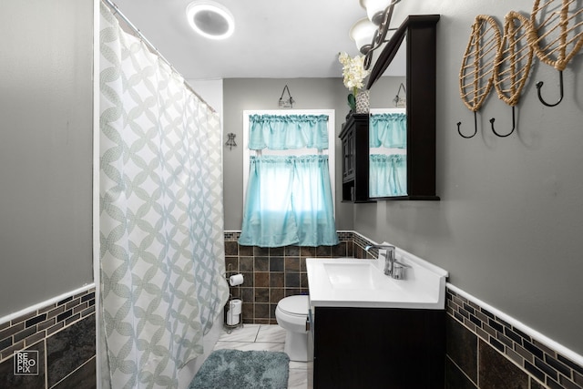 bathroom with vanity, toilet, and tile walls