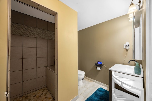 bathroom with tiled shower, vanity, and toilet