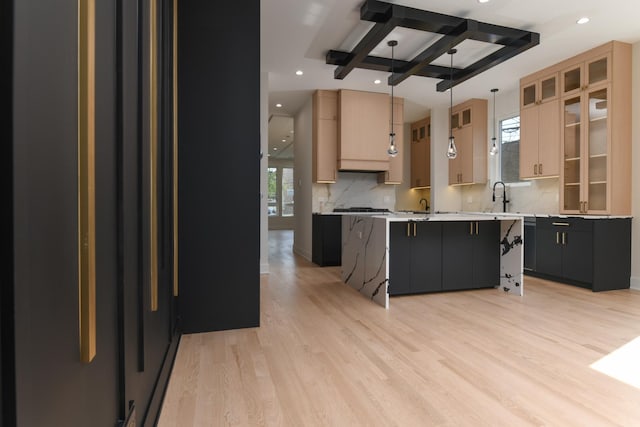 kitchen featuring a center island, tasteful backsplash, light hardwood / wood-style flooring, decorative light fixtures, and light brown cabinetry