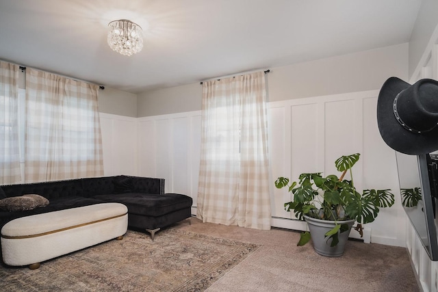 carpeted living room featuring a baseboard radiator and an inviting chandelier