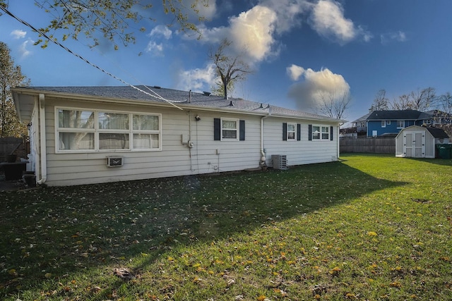 rear view of property with central AC unit, a storage shed, and a yard