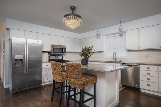 kitchen featuring appliances with stainless steel finishes, dark wood-type flooring, sink, white cabinets, and a kitchen island