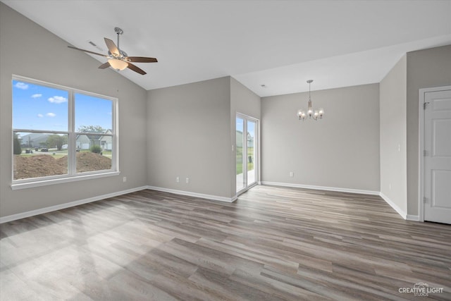 spare room featuring hardwood / wood-style floors, ceiling fan with notable chandelier, and lofted ceiling