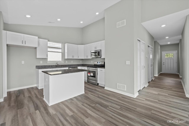 kitchen with appliances with stainless steel finishes, white cabinetry, a kitchen island, and a wealth of natural light