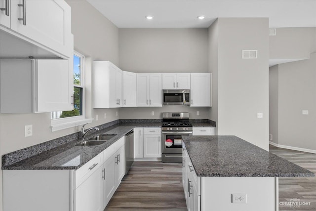 kitchen featuring white cabinetry, sink, stainless steel appliances, dark hardwood / wood-style floors, and dark stone counters