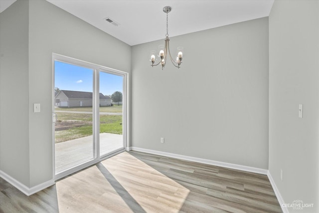 unfurnished dining area with wood-type flooring and an inviting chandelier