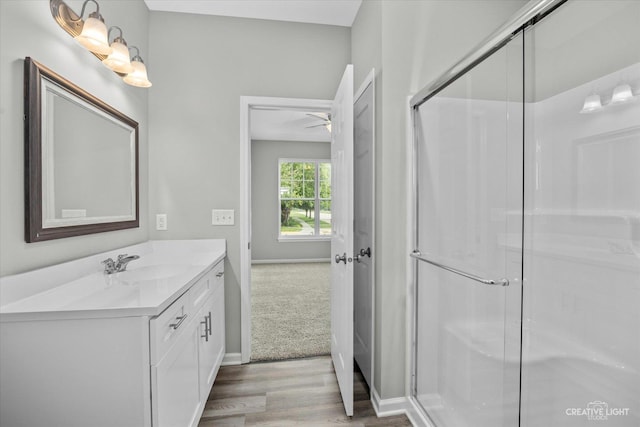 bathroom featuring walk in shower, wood-type flooring, vanity, and ceiling fan