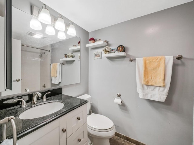 bathroom with tiled shower, vanity, and toilet