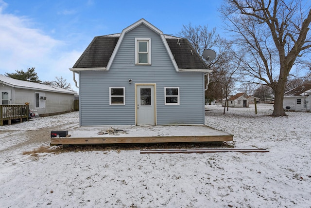 snow covered back of property featuring a wooden deck