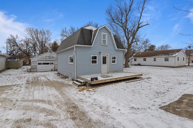 snow covered rear of property featuring a garage and an outdoor structure