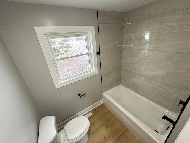 bathroom with hardwood / wood-style floors, shower / bathtub combination, and toilet