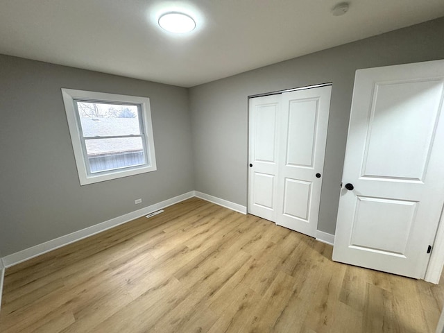 unfurnished bedroom featuring light hardwood / wood-style flooring and a closet