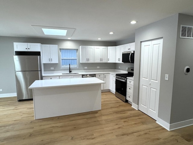 kitchen featuring a kitchen island, white cabinetry, appliances with stainless steel finishes, and a skylight