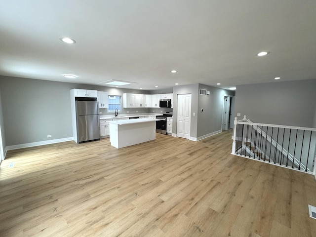 kitchen featuring a center island, white cabinets, sink, light wood-type flooring, and stainless steel appliances