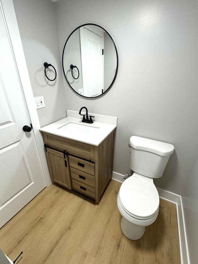 bathroom with hardwood / wood-style floors, vanity, and toilet