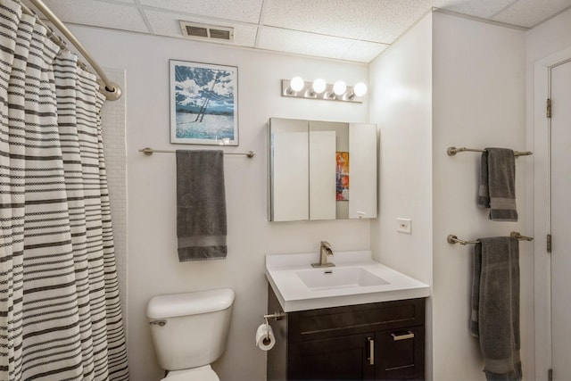 bathroom with vanity, toilet, a drop ceiling, and curtained shower