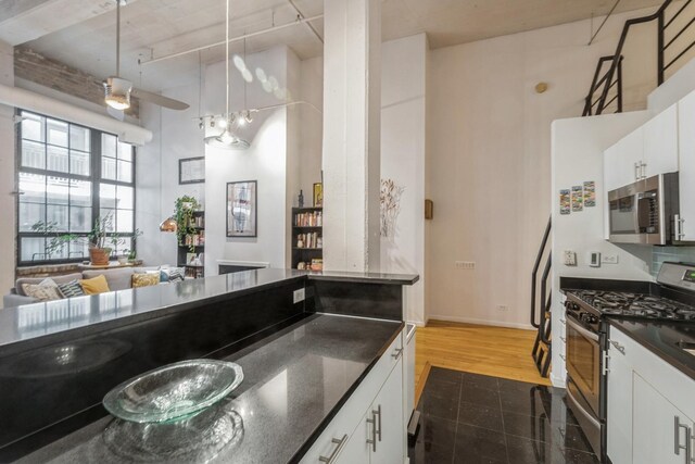 kitchen with appliances with stainless steel finishes, white cabinetry, ceiling fan, and pendant lighting