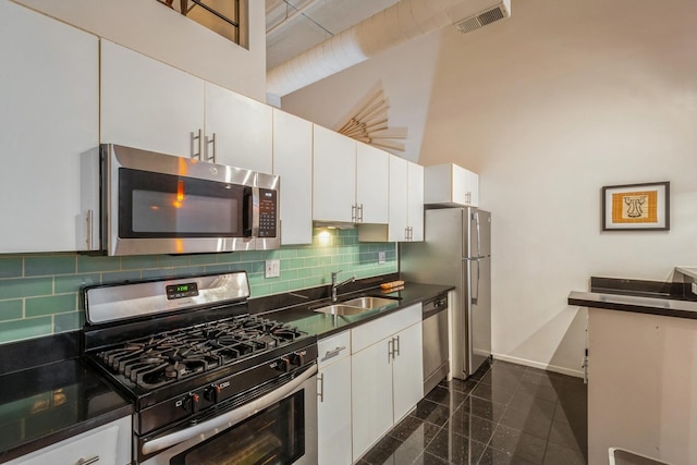 kitchen with white cabinets, a high ceiling, and stainless steel appliances