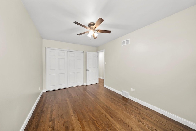 unfurnished bedroom featuring ceiling fan, a closet, and dark wood-type flooring