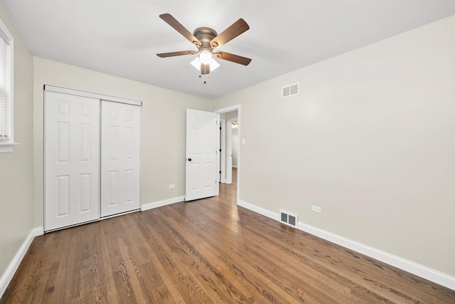 unfurnished bedroom featuring ceiling fan, a closet, and dark wood-type flooring