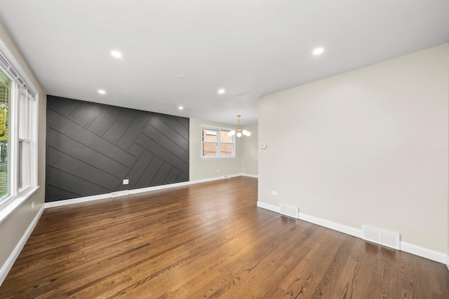 empty room with dark hardwood / wood-style floors and a notable chandelier